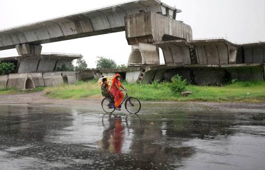 Dos personas subidas a una bicicleta en medio de la lluvia este martes en Calcuta, una jornada en la que se espera la llegada del ciclón Amphan a la zona de Bengala (India).