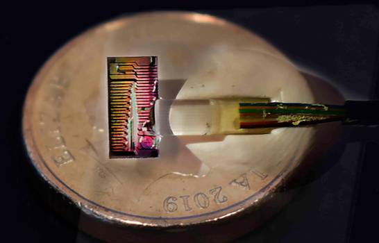 Chip de micropeine sobre una moneda australiana. Este pequeño chip produce un arco iris de luz infrarroja, equivalente a 80 láseres.