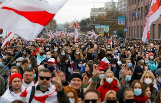 Una multitud de opositores marcha con antiguas banderas bielorrusas en protesta por los resultados de las elecciones presidenciales, el domingo 25 de octubre de 2020, en Minsk, Bielorrusia. (AP Foto)